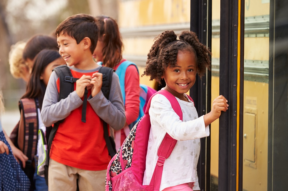 Child with backpack and school bus