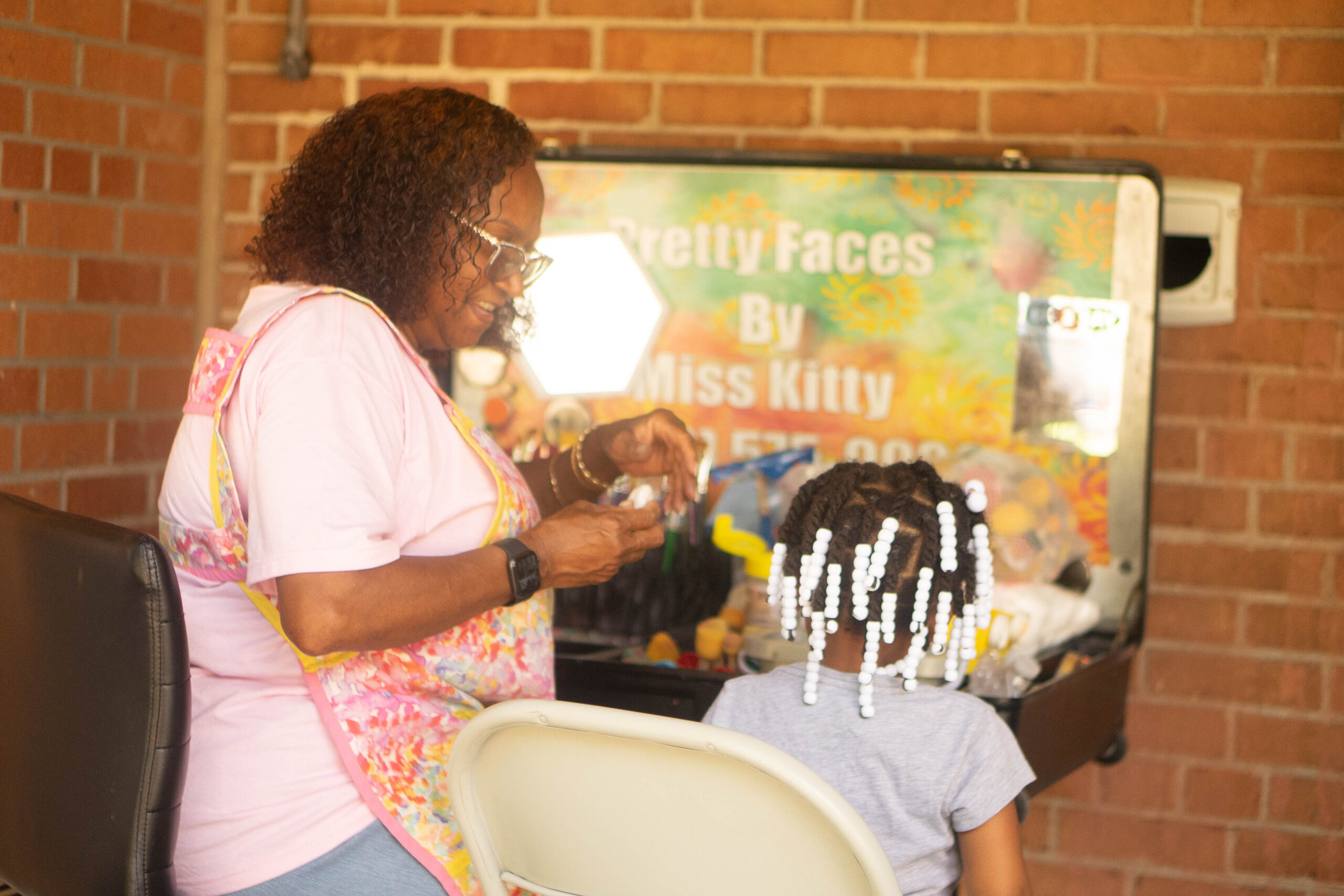 James Cole Foundation Event COTS, woman braiding girls hair