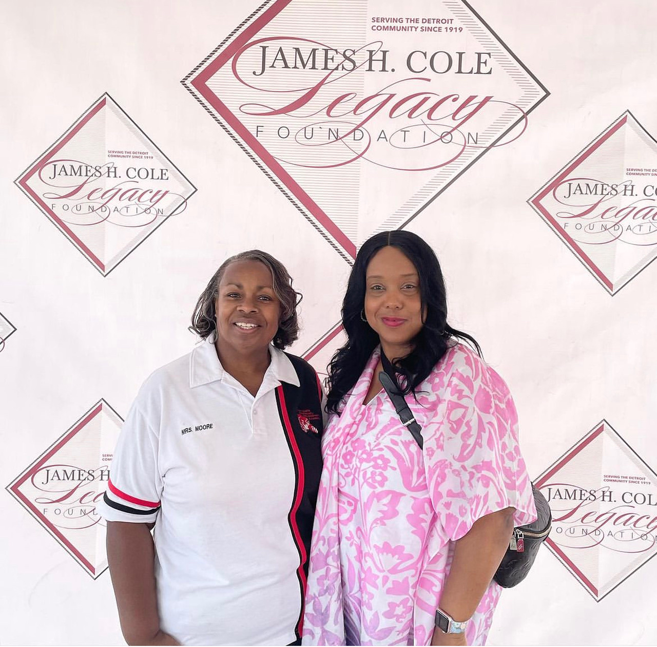 Two women standing behind James Cole Legacy Foundation sign
